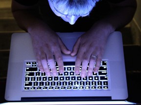 A man looks at a computer screen in a dimly lit room in a photo taken from above