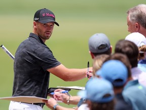 Wyndham Clark looks on as he signs his autograph for a fan during a practice round prior to the U.S. Open.