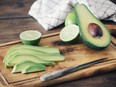 Sliced avocado and limes on a cutting board.