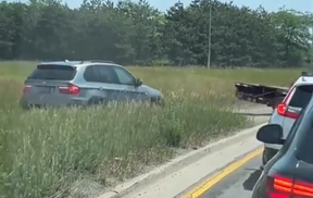 A BMW trails a flatbed truck out of a grassy field after leaving the 401 near Dixie Rd. in Mississauga.