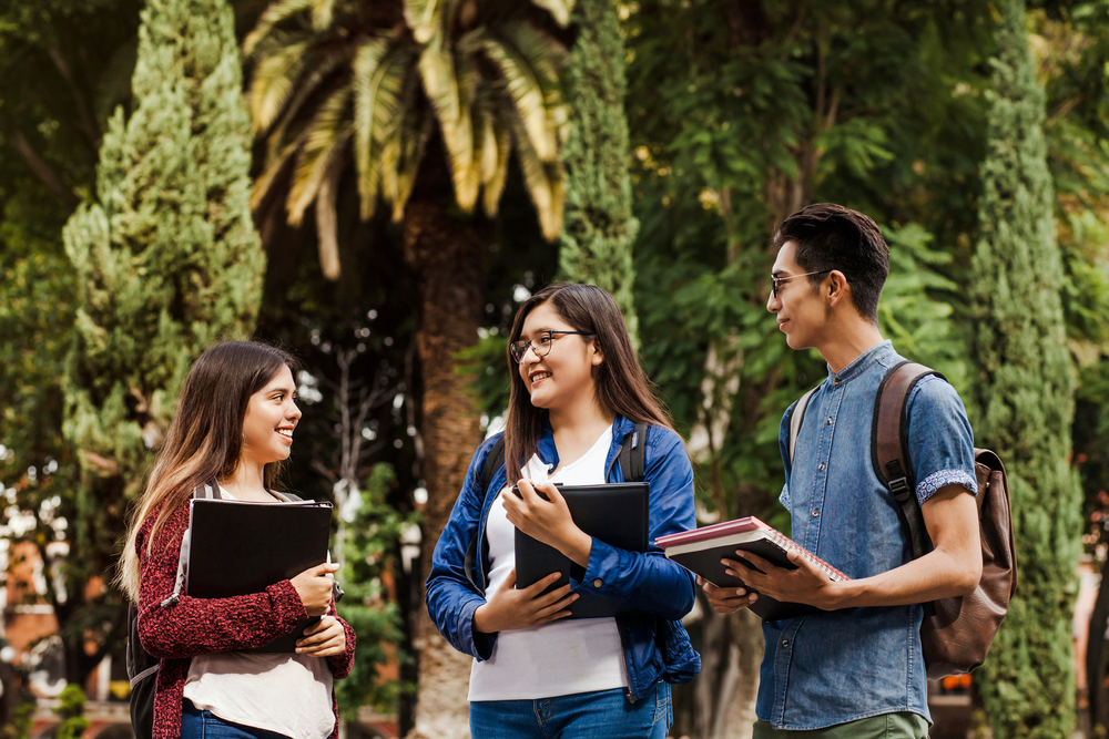 Iliustración para nota sobre países que ofrecen residencia permanente a estudiantes. Tres jóvenes universitarios con sus útiles.