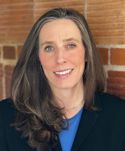 image of person in black blazer with blue shirt posing for headshot