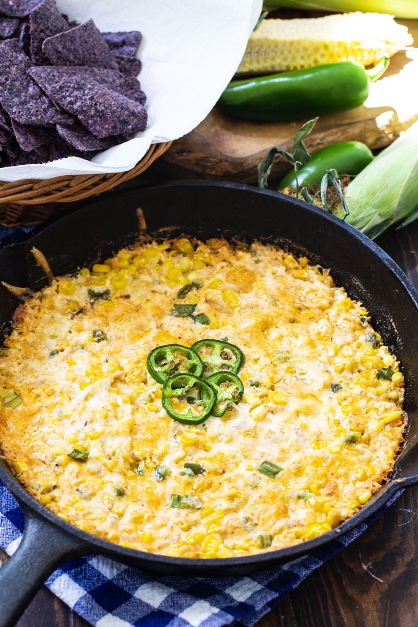 Hot Corn Dip with Jalapenos in cast iron pan with tortilla chips in background