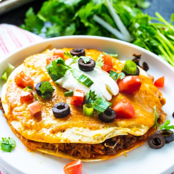 Taco Bell Mexican Pizza topped with sour cream on a plate.