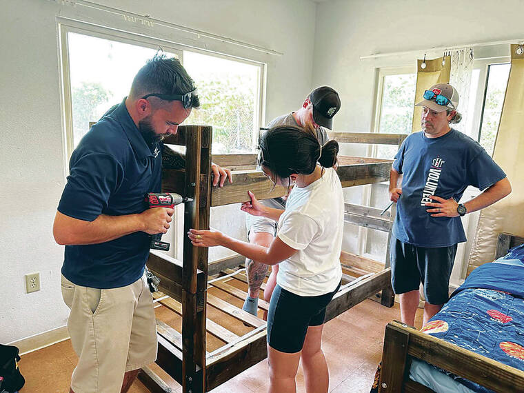 Volunteers build beds for keiki