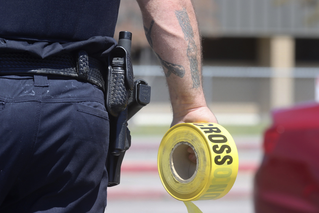 A police officer holds a roll of caution tape.