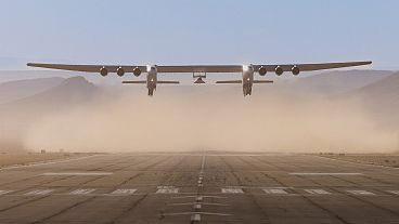 El avión Roc de seis motores despega con el vehículo de pruebas Talon-A-1 acoplado bajo sus alas.