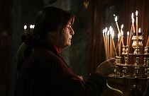 Una donna accende una candela durante la Divina Liturgia di Natale, nella chiesa greco-ortodossa di Panagia (Vergine Maria) Kapnikarea ad Atene, 25/12/2023