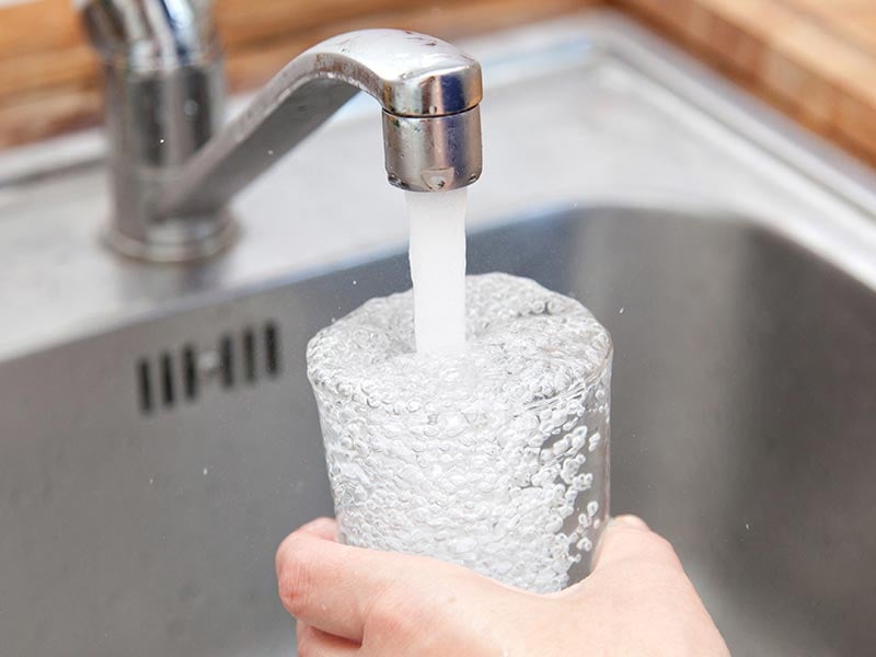 Glass being filled up in kitchen sink