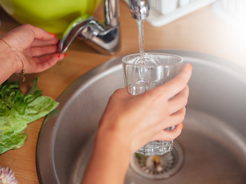 Glass being filled up in kitchen sink