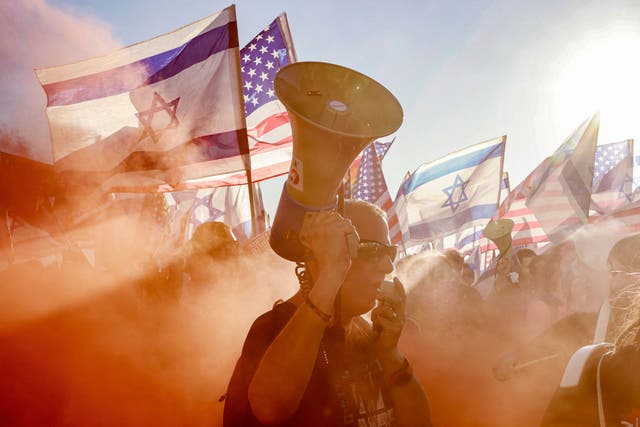 <p>A demonstrator marches through the smoke of a flare during a protest against the Israeli government's judicial overhaul bill outside the US Embassy in Tel Aviv</p>