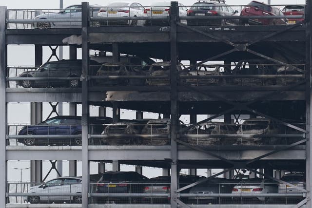 The burned-out shells of cars, buried among debris of a multi-storey car park at Luton Airport, Wednesday, after fire ripped through the structure (Jacob King/PA)