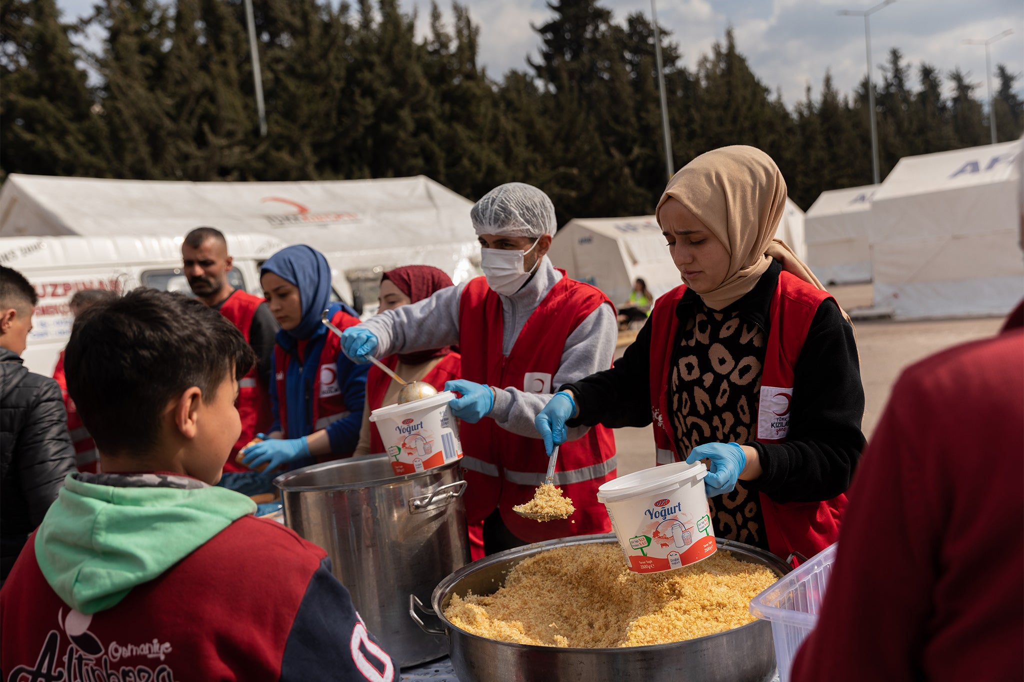 Families queuing for food distribution at a Turkish Red Crescent camp housing some of the tens of thousands of people displaced by the earthquakes in Osmaniye