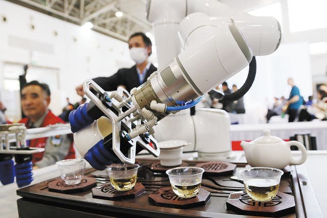 <p>A robot serves tea to visitors during a tea expo in Beijing in April</p>