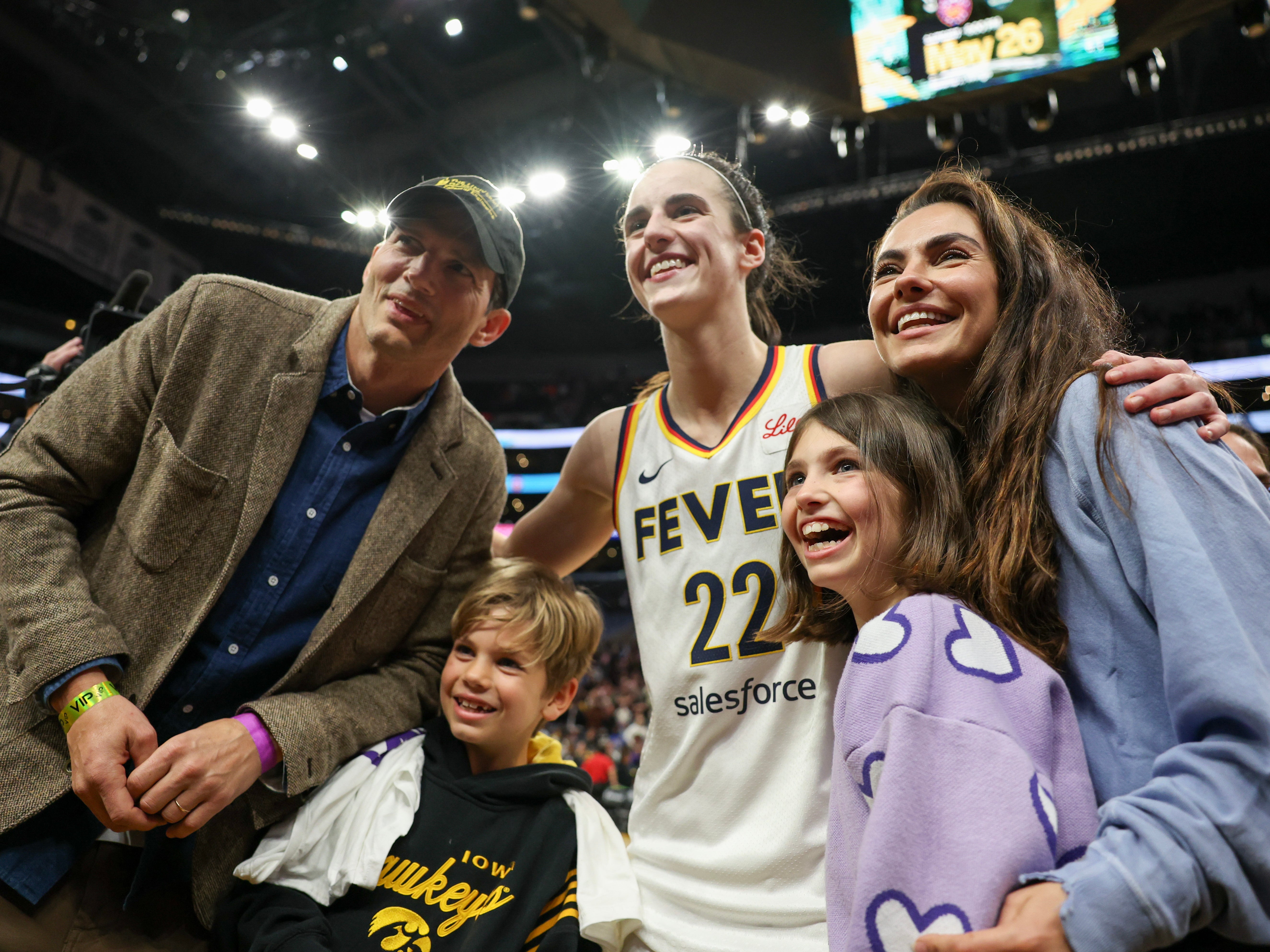 Caitlin Clark of the Indiana Fever poses for a photo with Ashton Kutcher and Mila Kunis with daughter Wyatt and son Dimitri