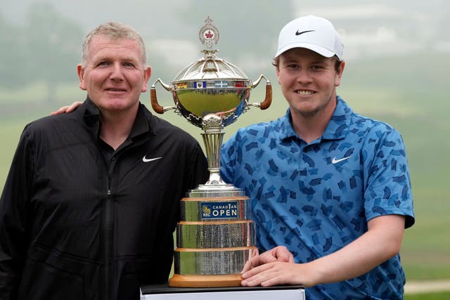 Scotland’s Robert MacIntyre, right, and his father and caddie, Dougie MacIntyre pose for photos with the trophy after winning the RBC Canadian Open (Frank Gunn/The Canadian Press via AP)