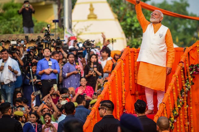 <p>Indian prime minister Narendra Modi greets supporters during his roadshow on 13 May 2024 in Varanasi, India</p>