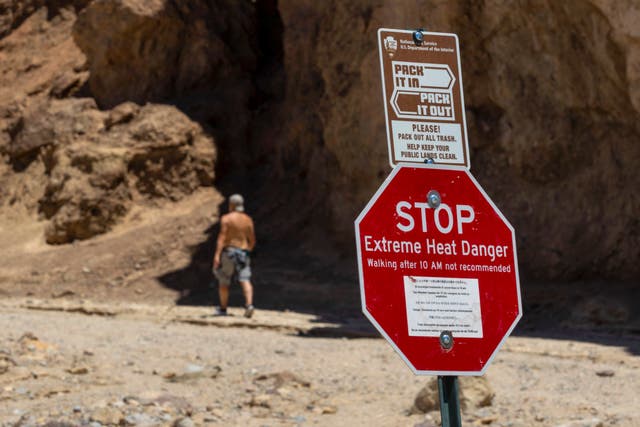 <p>A hiker passes a sign warning of extreme heat at the start of the Golden Canyon trail, in Death Valley National Park, California, which may experience the hottest week ever recorded on Earth </p>