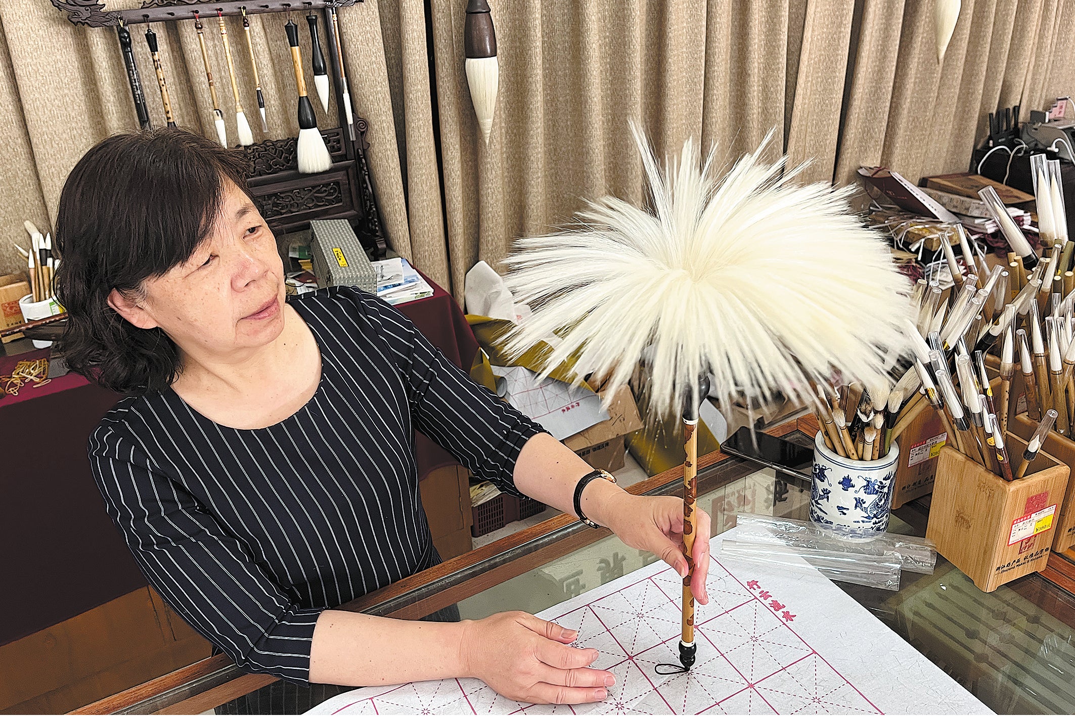 An artisan shows one of the best writing brushes produced by the Shanlian Huzhou Ink Brush Factory