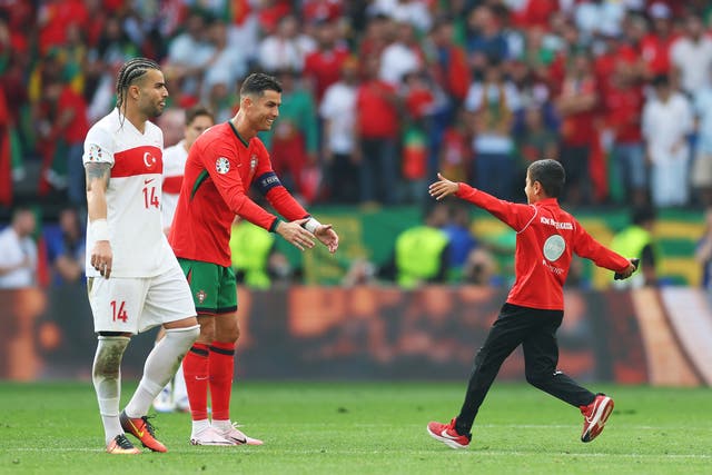 <p>Cristiano Ronaldo reaches out to hug a young pitch invader </p>