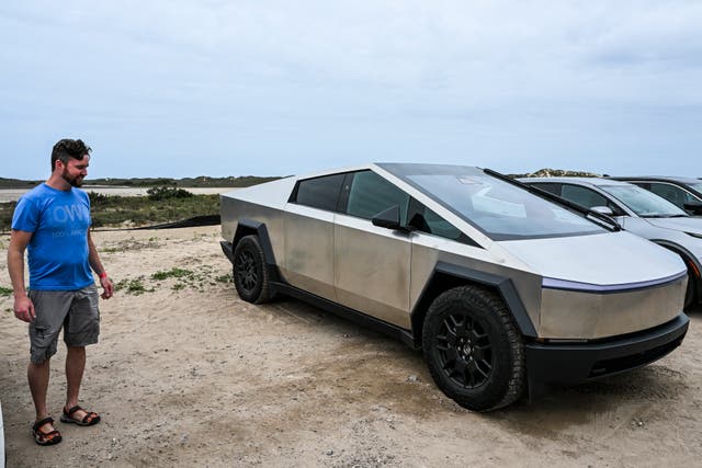 <p>A man looks at a Tesla Cybertruck parked near the SpaceX Starship as it stands on the launch pad ahead of its third flight test from Starbase in Boca Chica, Texas on March 12, 2024</p>