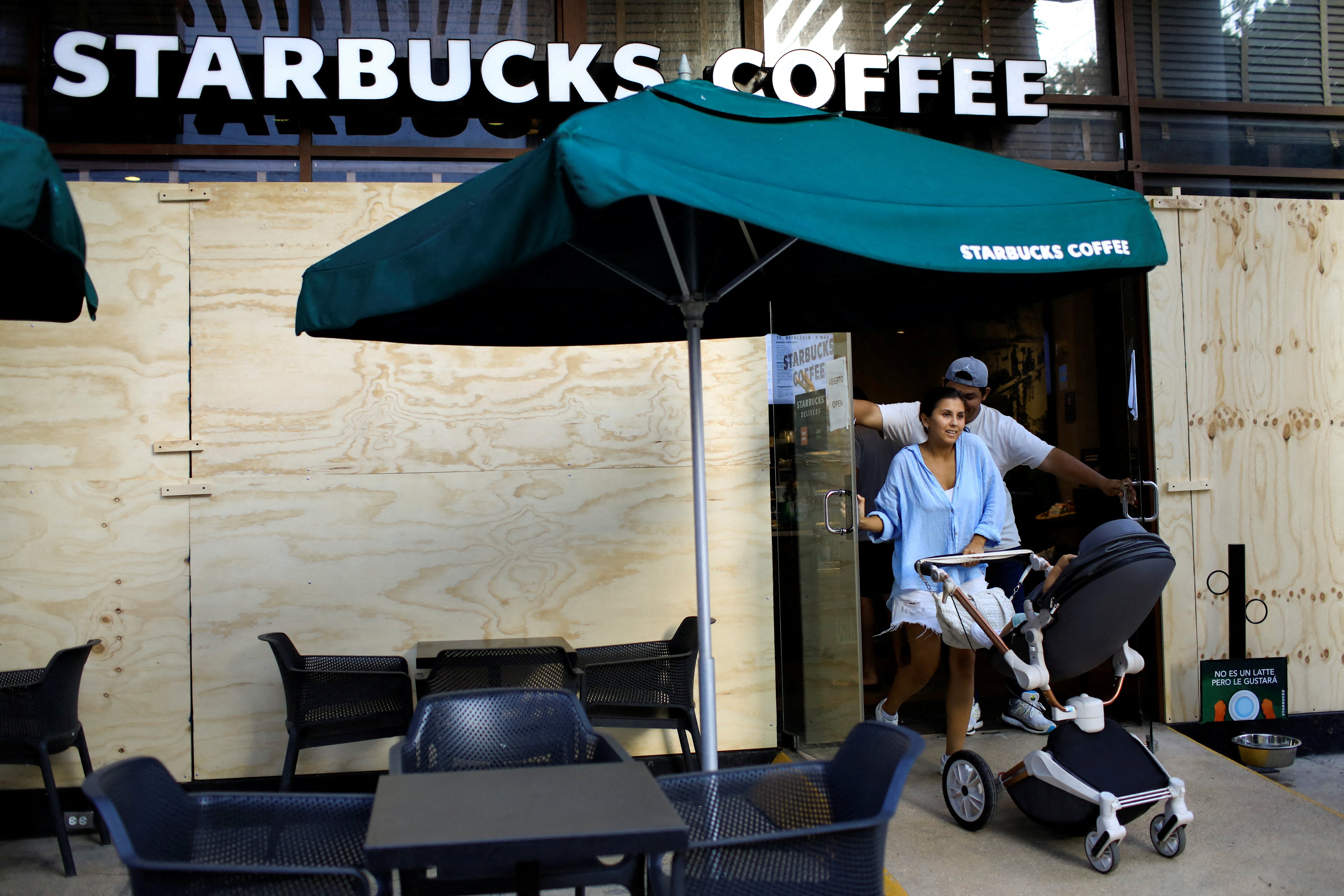 People exit from a boarded up Starbucks Coffee store ahead of the arrival of Hurricane Beryl, in Playa del Carmen, Mexico July 3, 2024