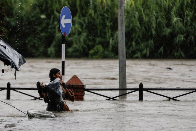 <p>A woman carrying her belongings wades through a flooded road in Kathmandu, Nepal</p>