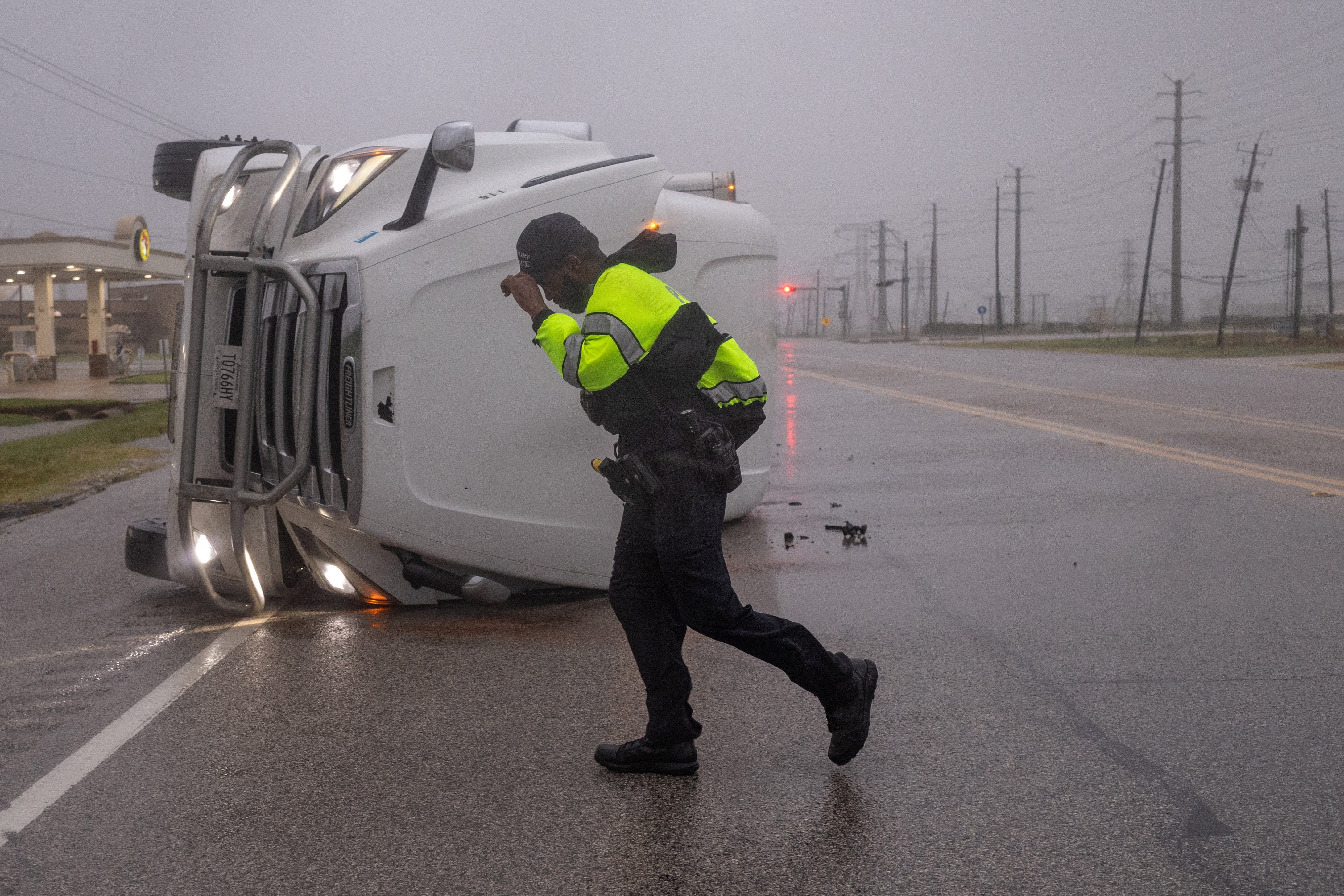 A police officer fights fierce winds from Hurricane Beryl as he searches for occupants of an overturned semi-trailer truck in Freeport, Texas, U.S., July 8, 2024