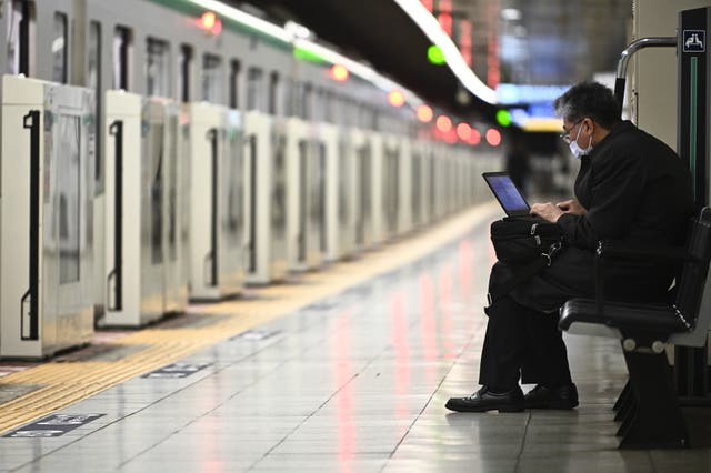 <p>Representational. A man works on his laptop at a train station in China </p>