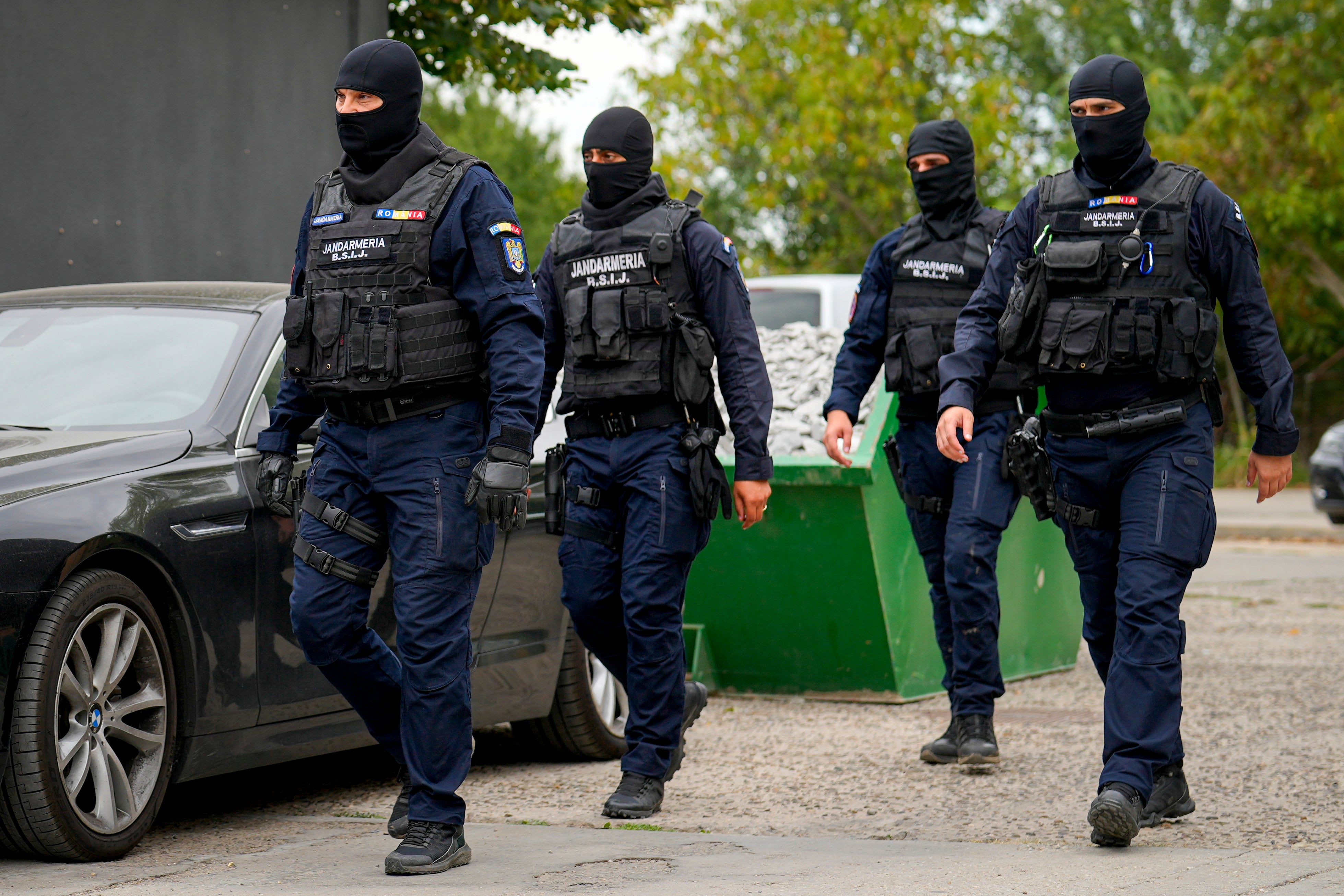 Gendarmes wearing balaclavas walk outside the residence of Andrew Tate during an early morning police search raid on the outskirts of Bucharest in Romania on Wednesday