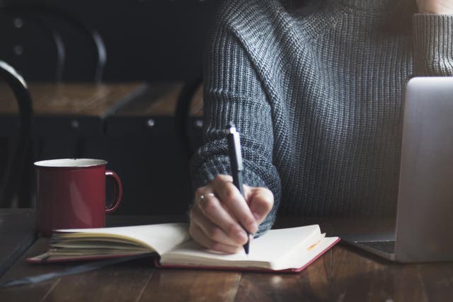 Woman writes with a coffee on table