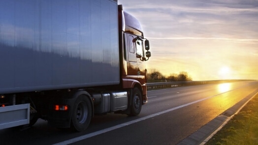 Truck travelling on a highway at sunset or sunrise