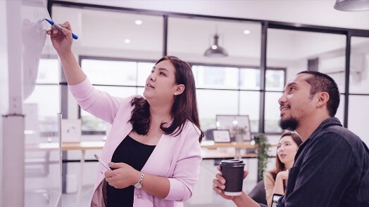 Three IT professionals collaborating at a whiteboard