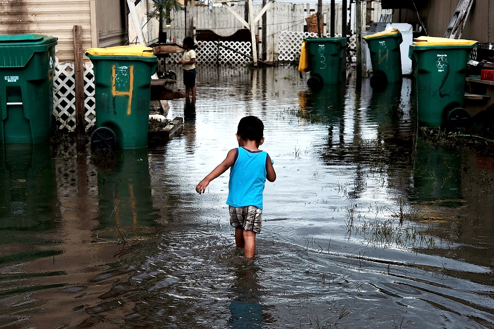 A child walking away from camera in flooded streets.