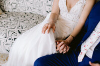 bride and groom hold hands sitting on black and white couch