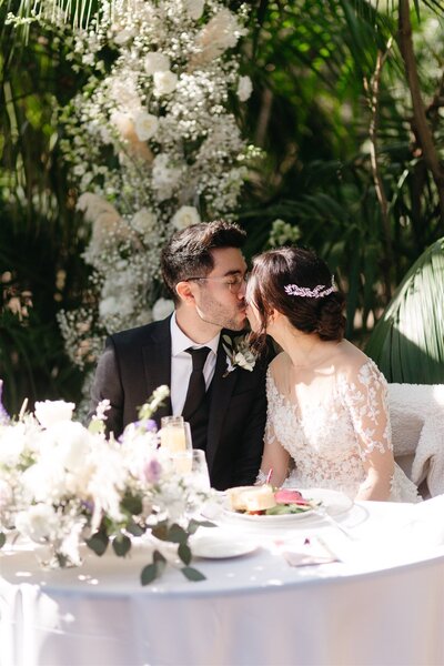 couple kiss at sweetheart table during wedding reception