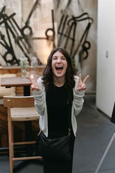 wedding planner Sarah laughing at camera and showing peace signs