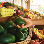 Person holding avocado in market.