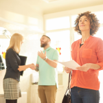 A couple standing in their new home; the man is shaking hands with a female realtor