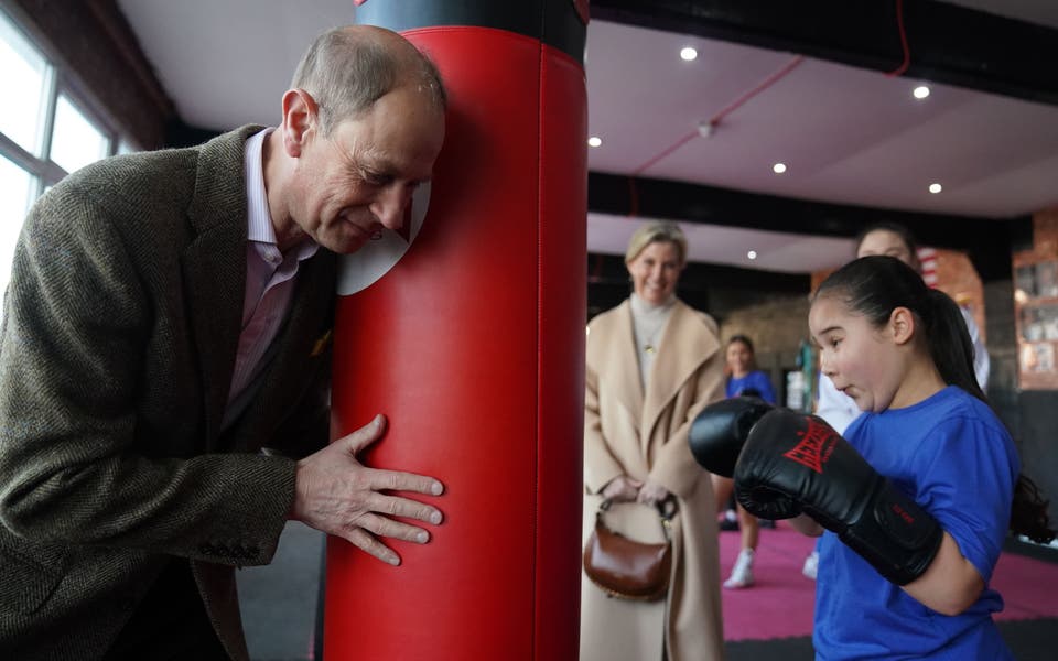 Edward holds the punchbag in sparring session with young boxer