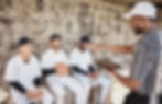 Coach talking to baseball players while holding a ipad 