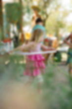 A little girl dances with a hula hoop in the desert