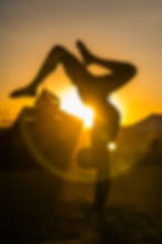 A man does a handstand in front of the setting sun