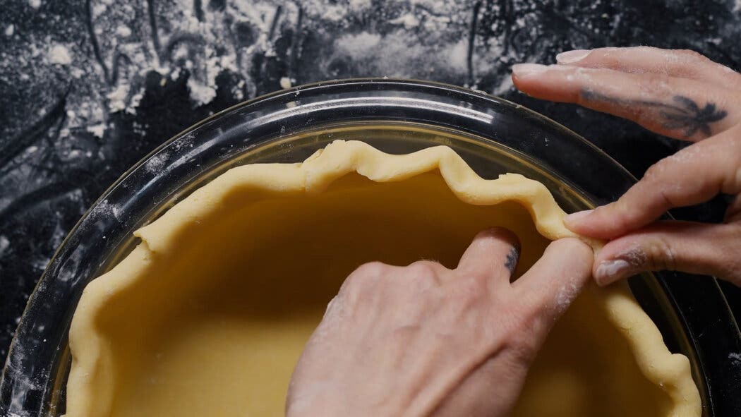 Image of pie dough being fit into a pie plate before baking. 