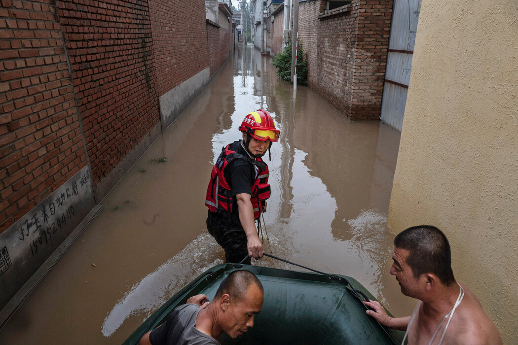 週四，一名救援人員在中國涿州附近的洪水地區拉動一艘載有居民的船隻。