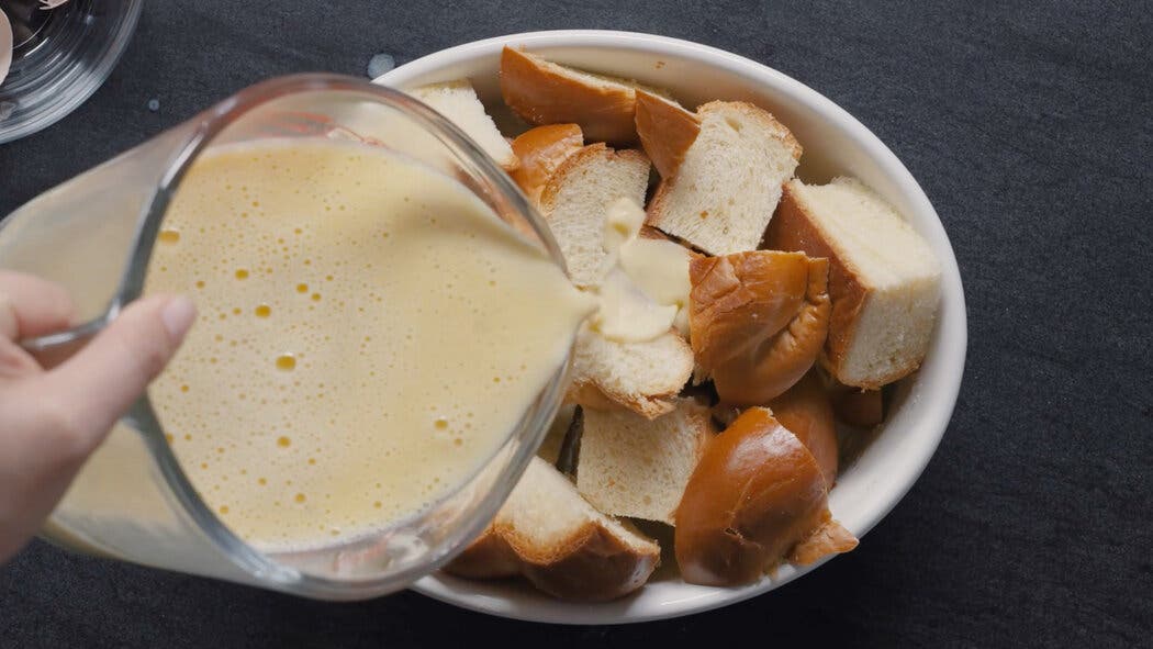 Image of milk mixture being poured over bread for making simple bread pudding