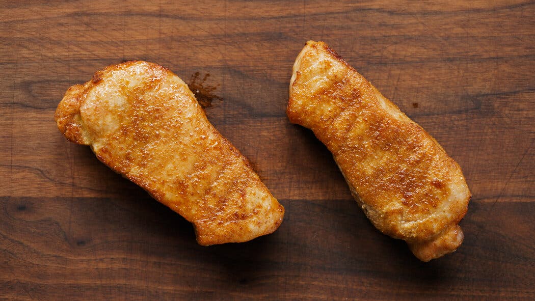 Image of cooked pork chops resting on a cutting board for making Air-Fryer Pork Chops.