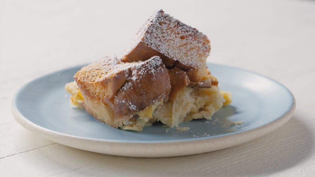 Image of a scoop of bread pudding on a plate with powdered sugar for making simple bread pudding.