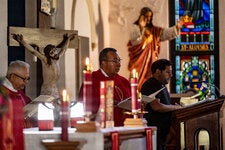 The Rev. Elias Lopez reading by candlelight during Sunday morning mass at All Saints Catholic Church in Houston. A storm on Thursday left the church without power, which has yet to be restored.