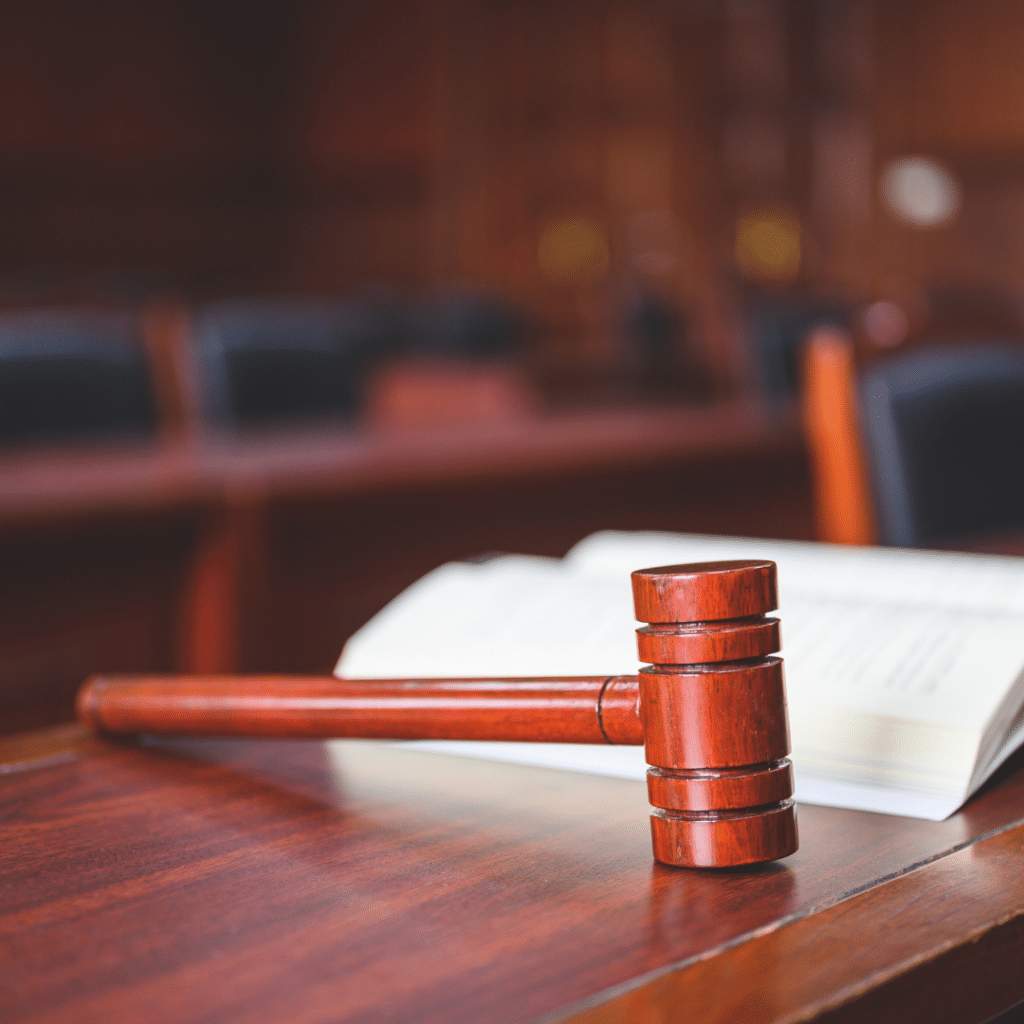 An empty courtroom with an open book on a table next to a wooden gavel.